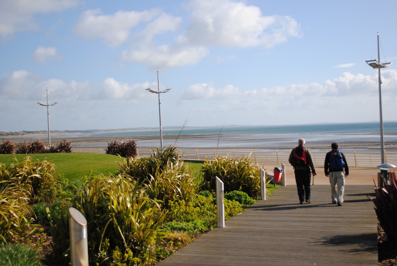 Two people walking along a path at a coastal community trail.