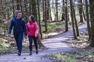 Man and women walk hand in hand through Drumkeeragh Forest