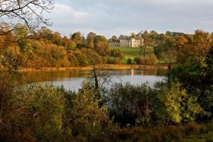 Castle Coole photographed across the lake surrounded by autumnal trees.