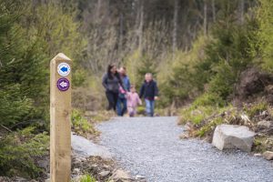 Waymarkers on a trail at Tievenadarragh with a family walking in the background